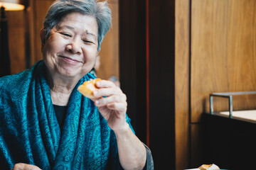 old asian elderly senior elder woman eating bread at restaurant. mature lifestyle