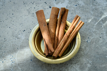 Cinnamon sticks in a bowl on a concrete table