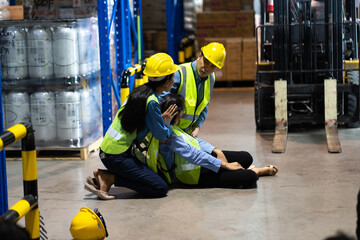 First Aid. Workers man and woman taking care female colleague lying on the floor in a warehouse. safety first and  insurance concept