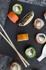Sushi set on gray concrete background. Rainbow sushi roll, uramaki, hosomaki and nigiri.
