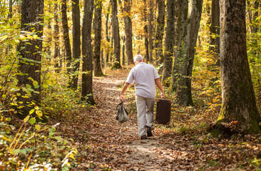 United with nature. Weekend in nature. Vacation and relax. Retirement concept. Elderly people. Mature man with white beard in forest. Hobby and leisure. Grandfather with vintage suitcase in nature