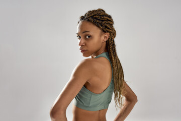 Portrait of a young attractive mixed race fitness model in sportswear looking at camera while posing isolated over grey background
