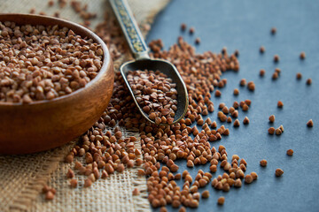 Buckwheat groats in a wooden bowl and vintage scoop. Close up on a black background. copy space for text.