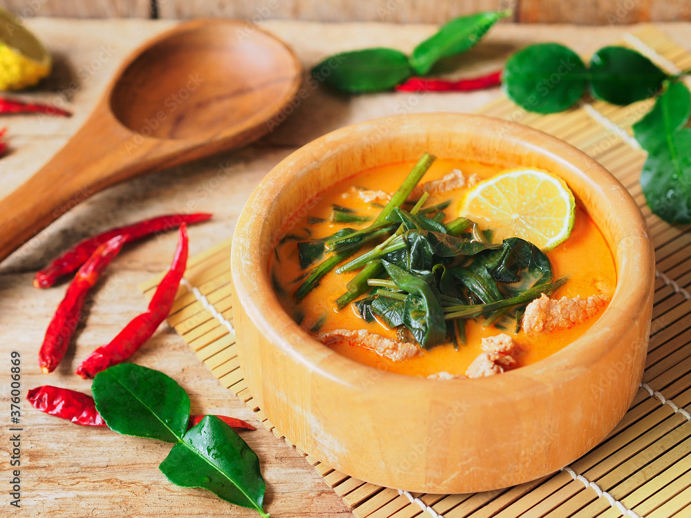 Wall mural Morning glory vegetable curry with pork meat in a wooden bowl, A traditional Thai food.