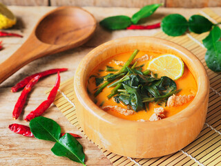 Morning glory vegetable curry with pork meat in a wooden bowl, A traditional Thai food.