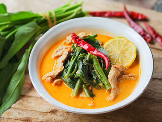 Morning glory vegetable curry with pork meat in a white color bowl, A traditional Thai food.