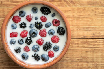Yogurt with blueberries, raspberries, blackberries, flax seeds in a clay bowl. Served vegetarian dish. Healthy breakfast, healthy food. Background for the menu of restaurants, cafes.