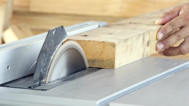 Close-up man hand carpenter sawing wooden with electric saw table machine for make equipment of furniture, Manufacturing industry and repair woodwork, Professional wood handyman use saw slicing timber