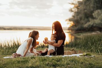 Happy family enjoying picnic in nature near the river. Family picnic. Concept of togetherness and relaxation.