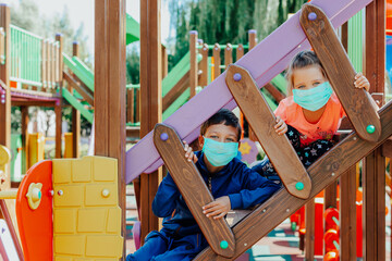 Children wearing protective masks playing on playground. 