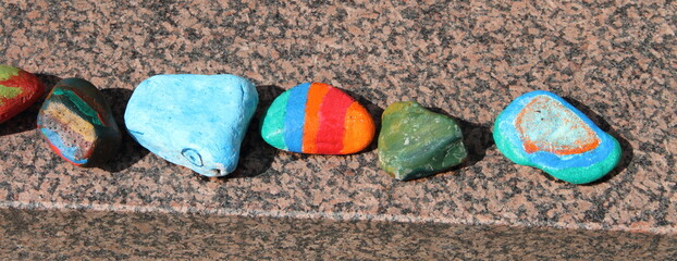 brightly painted pebbles on a brick wall