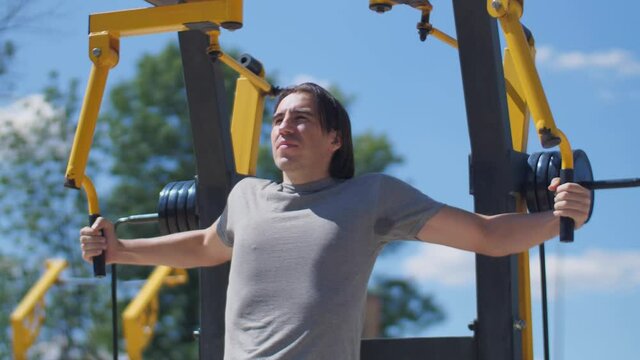 Long hair man trining pectoral muscules on fly machine