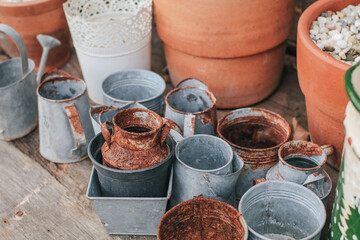 Old rustic metal silver pot and and brown-orange clay pot on a black wooden table outdoor in garden...