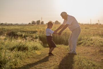 Happy senior man Grandfather with cute little boy grandson playing in field.