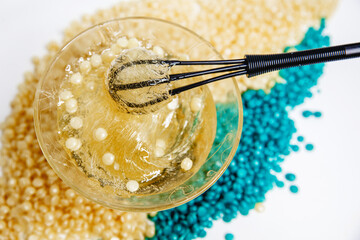 Glass jar with paste for sugaring close-up on the background of scattered pellet. The mixing process