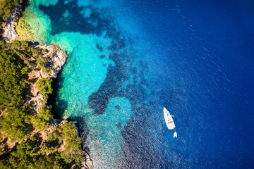 Fototapeta na wymiar A sailboat moored off the coast of Kefalonia, Ionian Islands, Greece, with blue and turquoise sea and green hills