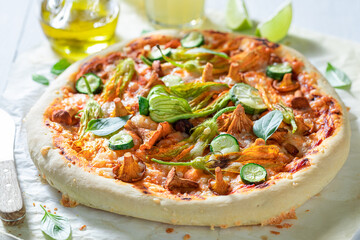 Tasty pizza with zucchini flower, chanterelles and mozzarella