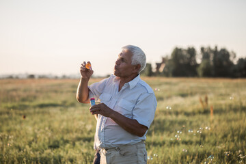 Senior man blowing soap bubbles while an excited male enjoys the bubbles.