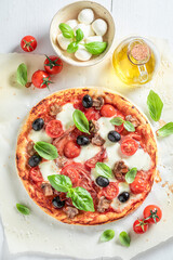 Homemade pizza Capricciosa made of tomatoes, cheese, olives and ham