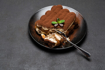 portion of Classic tiramisu dessert on ceramic plate on concrete background