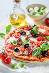 Rustic pizza Capricciosa with mozzarella, prosciutto and tomatoes