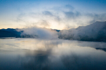 Lovely autumnal landscape with fog over the lake.