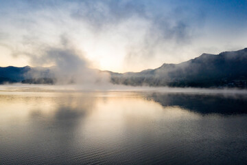 Lovely autumnal landscape with fog over the lake.