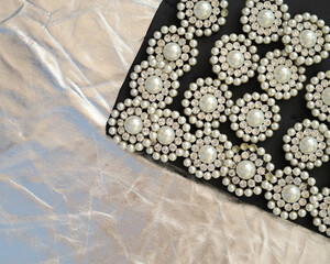 round brooch with pearls on a black and silver background.