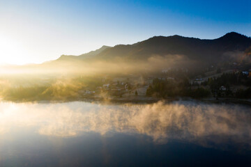 Lovely autumnal landscape with fog over the lake.