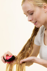 Blonde girl with long braid hair holds brush