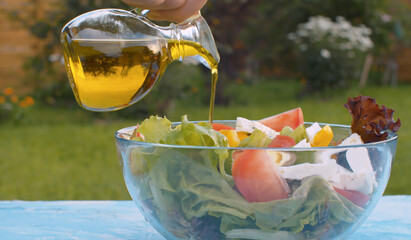 Olive oil pouring into bowl with salad
