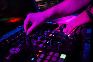 hands DJ playing and mixing music on music controller at a party