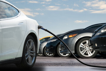 Close-up of a charging electric car on the background of parked cars