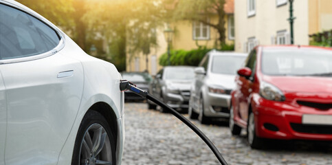 Close-up of a charging electric car on the background of parked cars