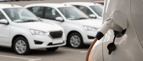 Close-up of a charging electric car on the background of parked cars