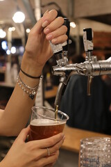 Female hand tapping beer during an evening event