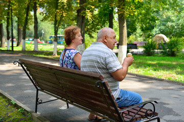 Grandparents sit on a bench and eat ice cream