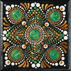 Mandala dot art painting on wood tiles. Beautiful mandala hand painted by colorful dots on black wood. National patterns with acrylic paints, handwork, dot painting. Abstract dotted background.