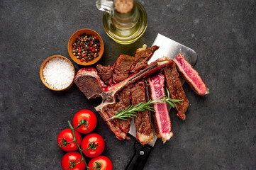 grill t-bone steak with ingredients on a meat knife on stone background