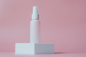 Pink plastic bottl container for cosmetics, on a white platform, on a pink background.