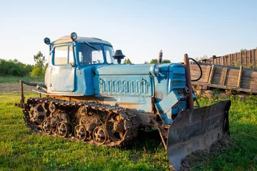 Fotobehang Rural farm field landscape. Soviet blue crawler bulldozer, front view © Roman Akimov