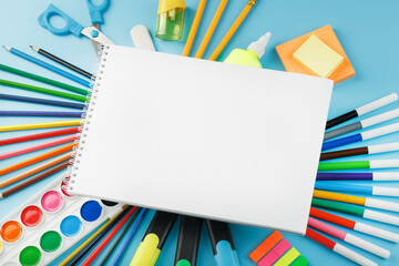 An album for drawing and creativity for school with stationery, a palette of colored paints, markers, brushes and pencils.