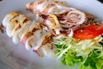 Grilled big squid serve in white disk with vegetable