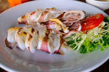 Grilled big squid serve in white disk with vegetable