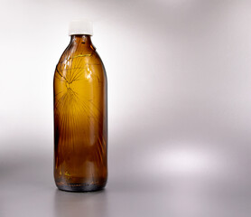 Cracked chemical glass bottle stock images. Broken chemical brown bottle isolated on a silver background with copy space for text. Broken brown bottle stock photo