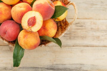 Fototapeta na wymiar Peaches in a basket on a wooden background with a slice of sliced juicy peach with a stone.