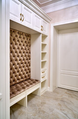 Classic white wardrobe with seating and shelves in contemporary bright hallway. Carriage coupler closet bench
