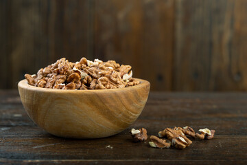 Walnut in wood bowl on wooden background with copy space