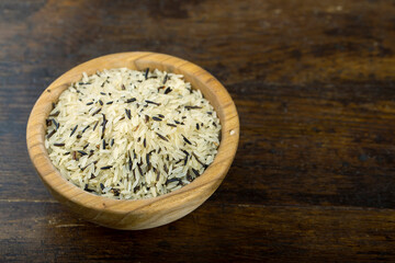 Wild rice in a wooden bowl on a wooden table.