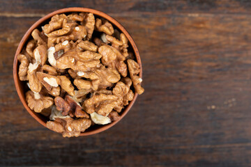 Walnut in clay bowl on wood background with copy space.